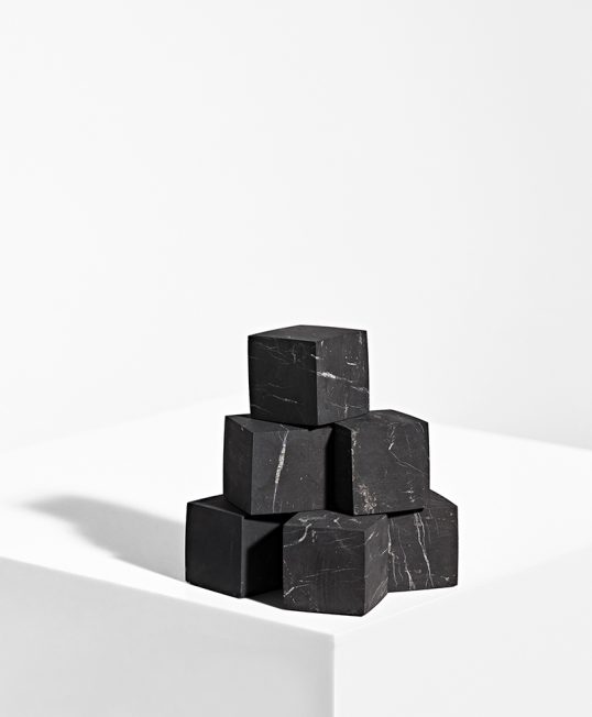Sorte shungit kuber som er stablet som en pyramide på hvid baggrund