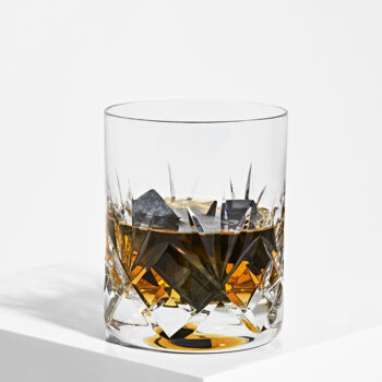 Fine sorte Shungit kuber brugt som isterninger i et glas whisky. Billedet er taget på hvid baggrund
