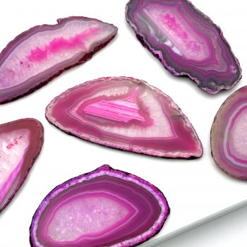 Skiver af pink sten med hvide detaljer og sort kant. Fotograferet på hvid baggrund