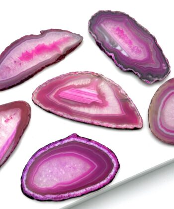Skiver af pink sten med hvide detaljer og sort kant. Fotograferet på hvid baggrund