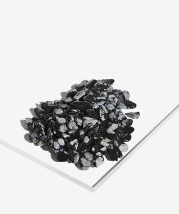 En hvid baggrund med Mange Minikrystaller. Grå og sort snefnug obsidian