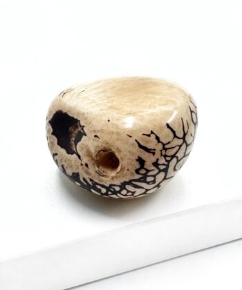 sten i beige med sorte snoninger på hvid baggrund